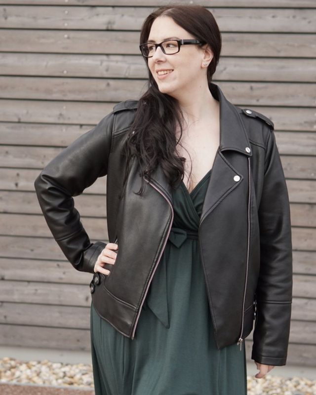Manu in Lederjacke vor einer Holzwand